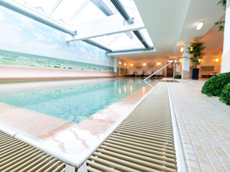Piscine intérieure moderne avec grandes fenêtres et ambiance détendue dans un hôtel.