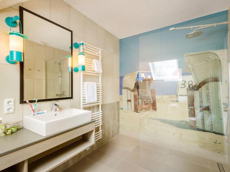 Moderne badkamer met grote spiegel, wastafel en inloopdouche met glazen afscheiding.