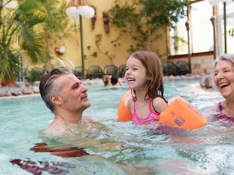 Drie generaties die samen genieten van zwemmen in een zwembad in een ontspannen sfeer.