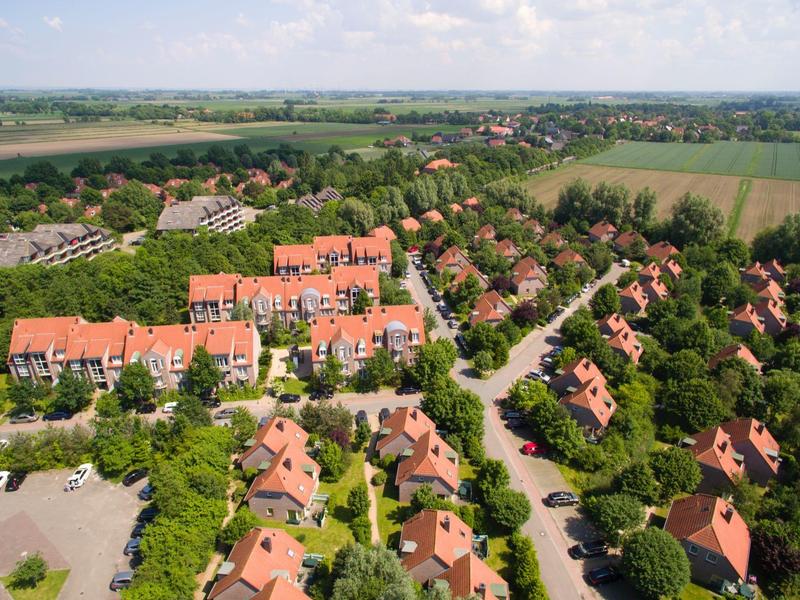 Luchtfoto van een vakantiepark met rode daken, omgeven door groene velden en bomen.
