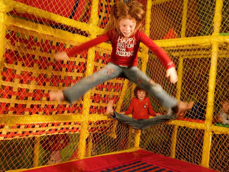 Enfant qui saute joyeusement dans un espace trampoline sécurisé.