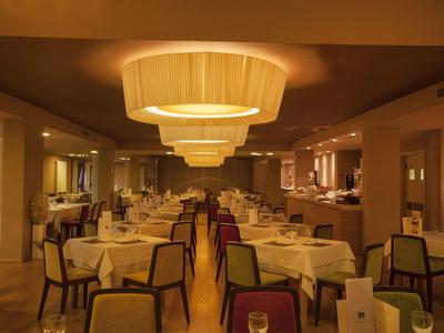 Elegantes Restaurant mit gedeckten Tischen und warmem, gelblich-orangenem Licht.