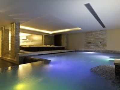 Innenpool mit stimmungsvoller Beleuchtung, Natursteinen und moderner Deckenbeleuchtung.