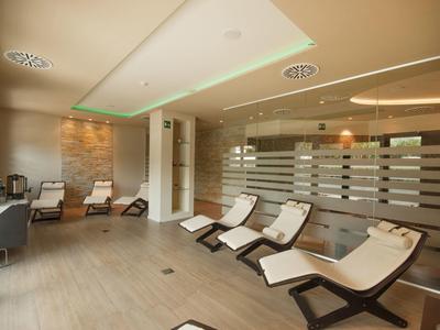 Moderner Ruheraum mit bequemen Liegestühlen, warmem Licht und Steinwandgestaltung.