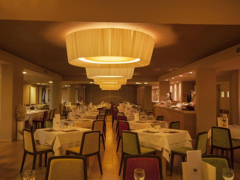 Elegantes Restaurant mit gedeckten Tischen und warmem, gelblich-orangenem Licht.