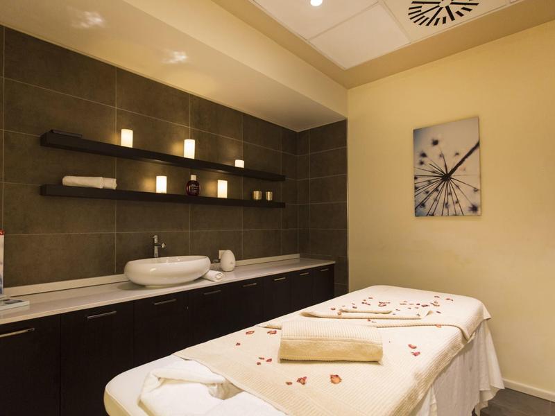 Behandlungsraum mit Massagebank, Handtüchern, beruhigender Beleuchtung und moderner Wanddekoration.