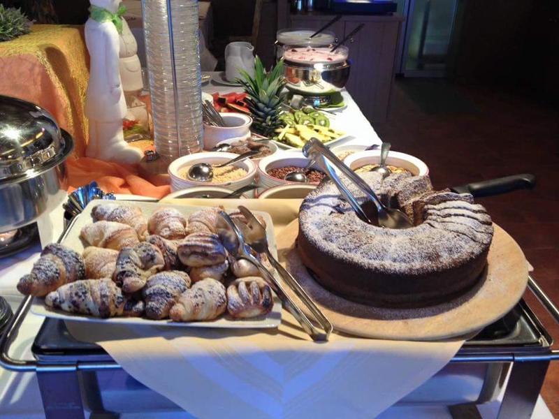 Ein Tisch mit verschiedenen Süßspeisen, darunter Schokoladenkuchen und Hörnchen mit Puderzucker.