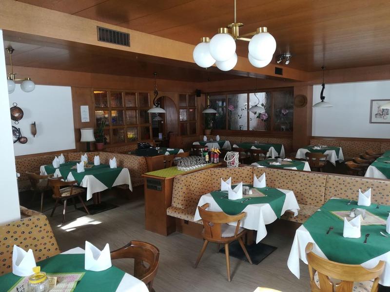 Gemütliches Restaurant mit grünen Tischdecken, weißen Servietten und Holzvertäfelung.