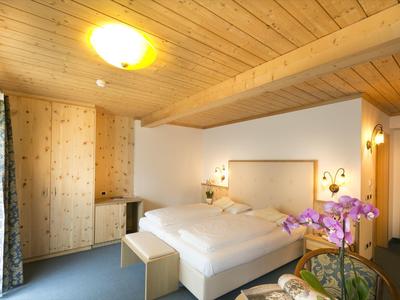 Gemütliches Schlafzimmer mit Holzwand, Doppelbett, Schrank, Orchidee und warmem Licht.