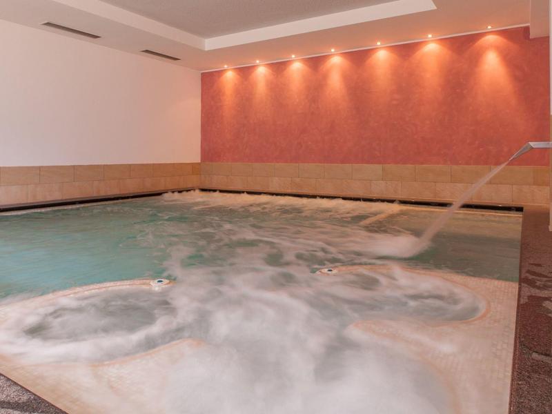 Innen-Whirlpool mit sprudelndem Wasser, Wasserstrahl und roter Wandbeleuchtung.