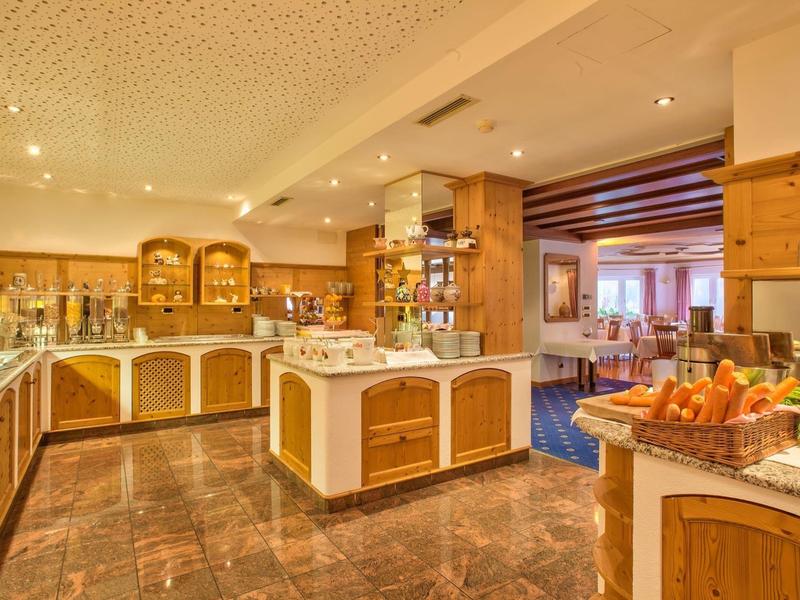 Große, helle Hotelküche mit Holzschränken, Marmorboden und Buffet-Theken mit Obst und Getränken.