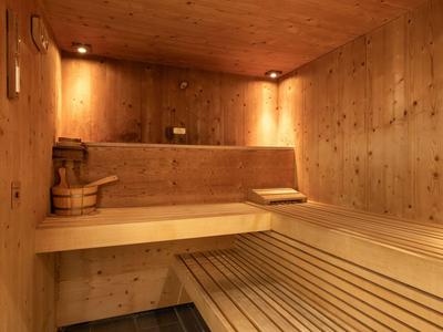 Holzsauna mit Bank, Eimer und Aufgusskelle in warmem Licht