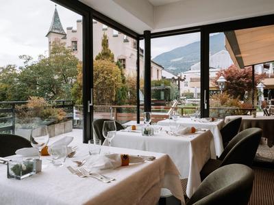 Gemütliches Restaurant mit gedeckten Tischen und Blick auf Stadt und Berge.