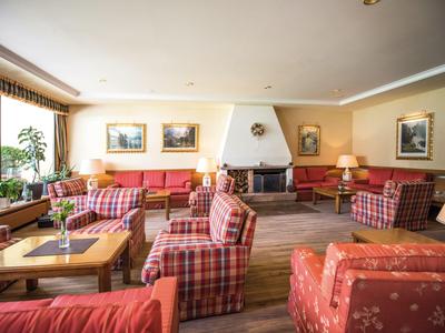 Gemütlicher Hotel-Loungebereich mit karierten Sesseln und Kamin in warmem Licht.