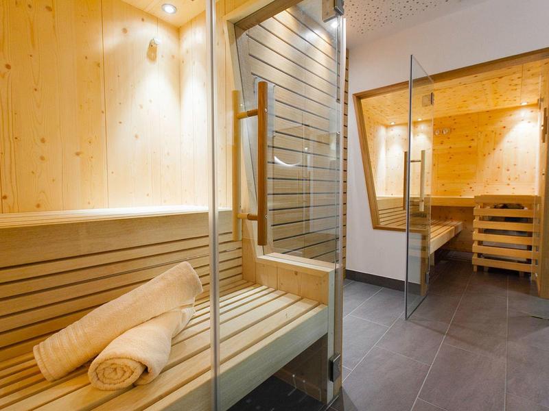 Helle Holzsauna mit Glaswänden, Holzbänken und aufgerollten weißen Handtüchern.