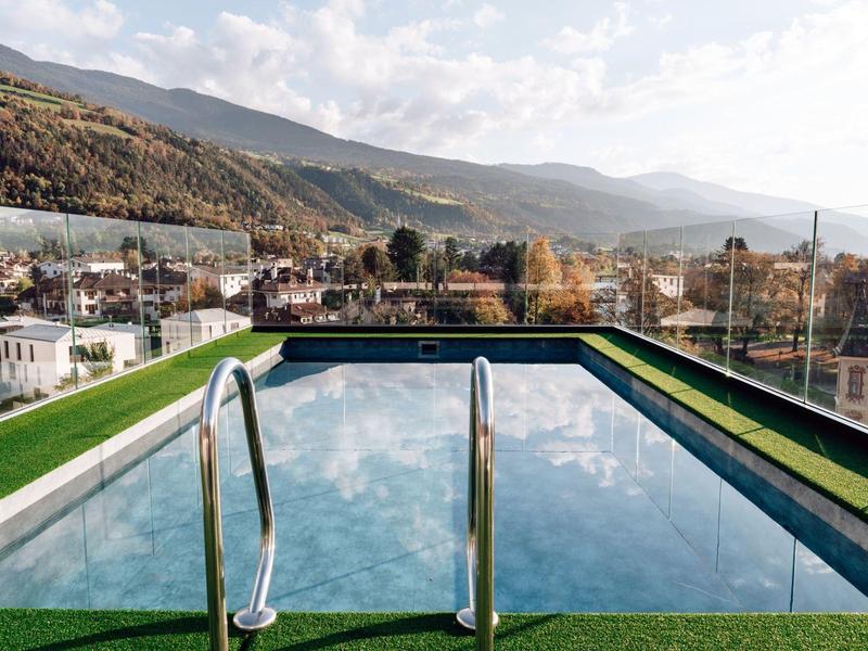 Ein kleiner rechteckiger Pool auf dem Dach mit Bergblick und grüner Kunstgrasumrandung.