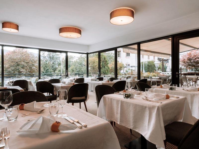 Modernes Restaurant mit weißen Tischdecken, Gläsern und großflächigen Fenstern für Tageslicht.