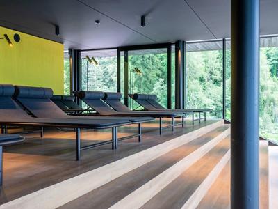 Moderner Ruheraum mit Liegen und großen Fenstern mit Blick ins Grüne.