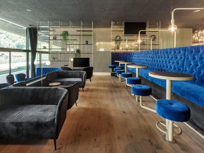 Moderner Hotel-Loungebereich mit blauen und schwarzen Sitzmöbeln auf Holzfußboden.