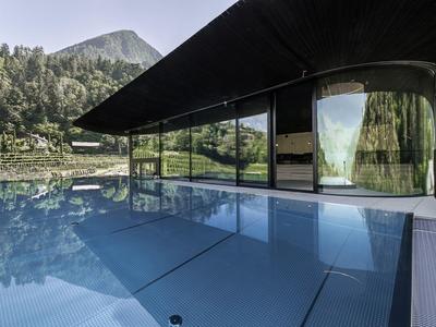 Moderner Pool mit Glaswand und Bergblick in einem Hotel.