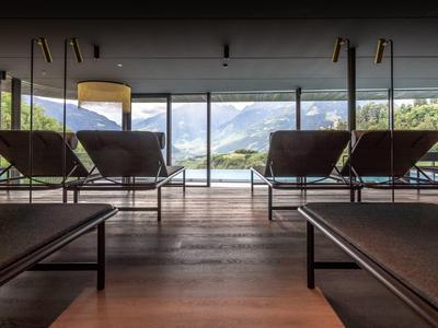 Moderner Ruheraum mit Liegen und Panoramablick auf die Berge durch große Fenster.