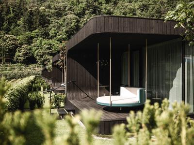 Moderner Balkon mit Schaukelbett vor bewaldetem Bergpanorama.