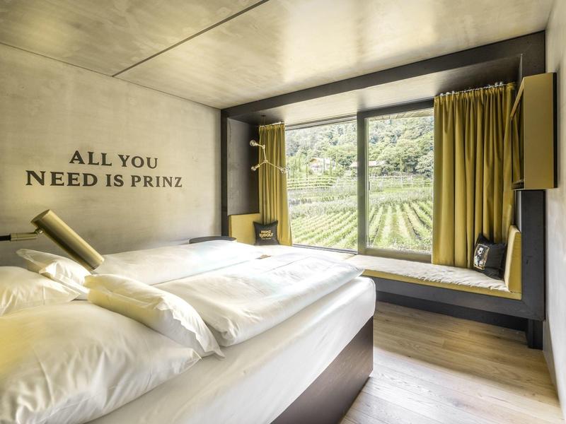 Gemütliches Hotelzimmer mit Doppelbett und großem Fenster mit Blick auf Weinberg.
