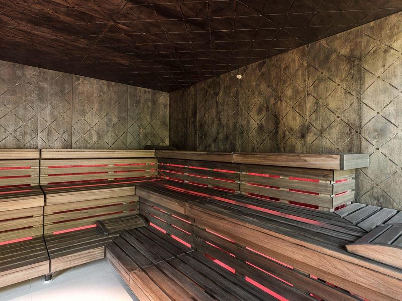 Moderner Saunaraum mit dreistufigen Holzsitzbänken und gedämpftem Licht.
