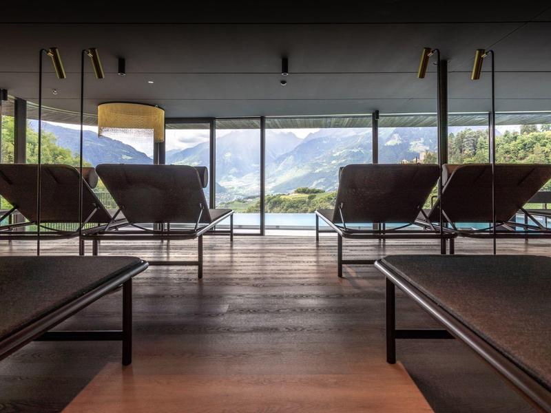 Moderner Ruheraum mit Liegen und Panoramablick auf die Berge durch große Fenster.