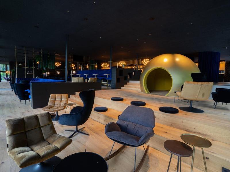 Moderner Lounge-Bereich mit Sesseln, Tischen und runden Sitzhöhlen in einem stilvollen Hotel.