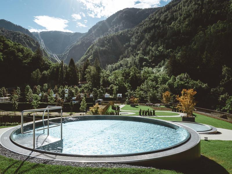 Rundes Außenpool mit Bergblick und grünem Garten in sonniger Lage.