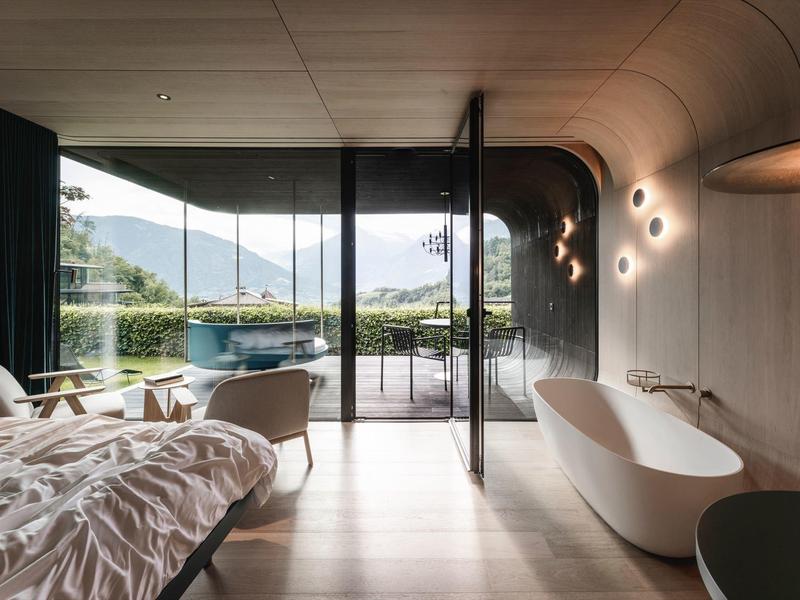 Modernes Hotelzimmer mit Badewanne und Panoramafenster mit Bergblick.