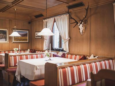 Gemütliches Restaurant mit Holzwänden, gestreiften Polstern und Hirschgeweih-Dekor.