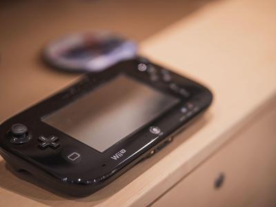 Schwarzer Nintendo Wii U Gamepad mit Buttons liegt auf einer hellen Holzoberfläche.