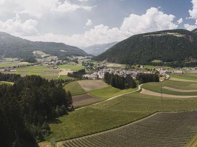 Weite grüne Felder, Hügel und Wälder unter bewölktem Himmel in ländlicher Landschaft.