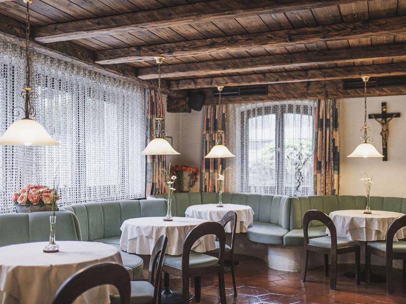 Gemütliches Restaurant mit runden Tischen, weißen Tischdecken und Holzstühlen in hellem Naturlicht.