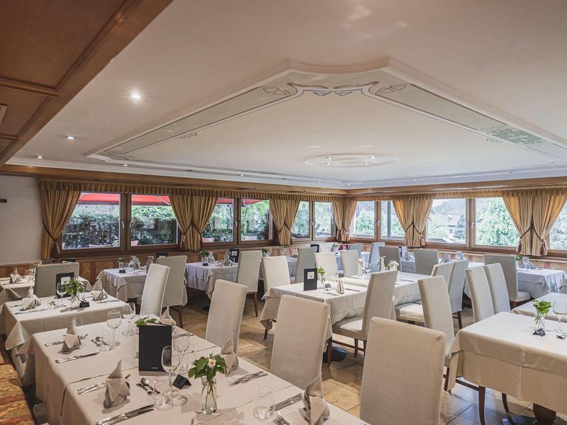 Hell eingerichteter Speisesaal mit weißen Tischen, bequemen Stühlen und großen Fenstern rundherum.