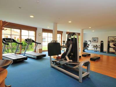 Moderner Fitnessraum mit Laufbändern, Kraftgeräten und Spiegeln, hell und geräumig.