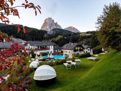 Hotelgarten mit Liegestühlen und Blick auf bewaldete Berge und Felsen im Hintergrund.