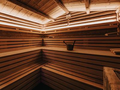 Innenraum einer Holzsauna mit mehrstufigen Bänken und Holzverkleidung, beleuchtet von warmem Licht.
