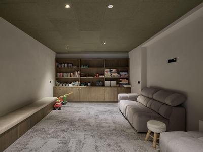 Moderner, minimalistisch eingerichteter Raum mit grauem Sofa, Hockern und Regalen an der Rückwand.