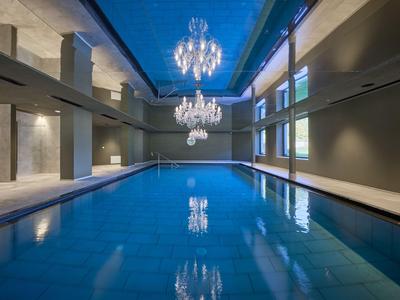 Innenpool mit blauer Wasserfläche, hohen Wänden und zwei großen Kronleuchtern an der Decke.