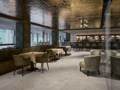 Eleganter Hotel-Loungebereich mit bequemen Sesseln, Tischen und Bar im Hintergrund.