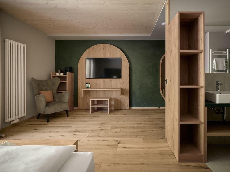 Moderner Hotelzimmerbereich mit Holzfußboden, grün gestrichener Wand und bequemen Möbeln.