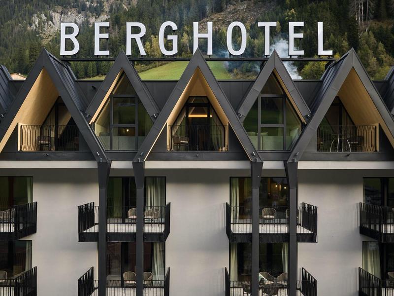 Blick auf ein Berghotel mit auffälliger Spitzdacharchitektur und großen Fenstern.