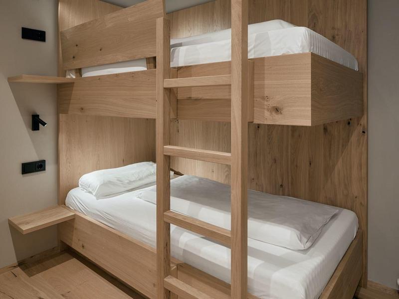 Holz-Etagenbett in einem einfachen, modernen Zimmer mit weißen Wänden und Holzboden.