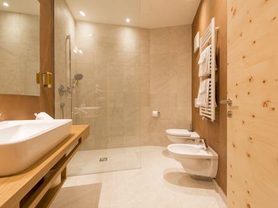 Modernes Badezimmer mit Dusche, Waschbecken und zwei Hänge-WCs in warmen Holztönen