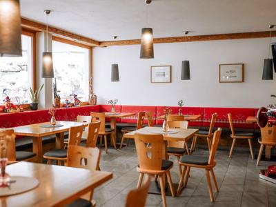 Helles Restaurant mit Holzstühlen, roten Sitzbänken und großen Fenstern mit Schneeblick.