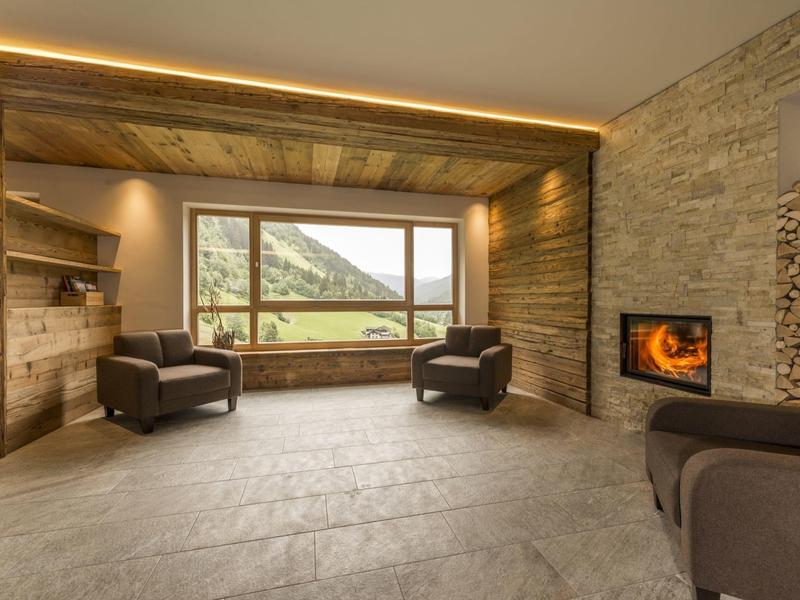 Gemütlicher moderner Wohnraum mit Kamin, Sitzmöbeln und großem Fenster mit Bergblick.