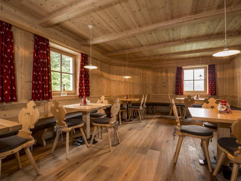 Gemütlicher Holzraum mit rustikalen Möbeln, roten Vorhängen und natürlichem Tageslicht.